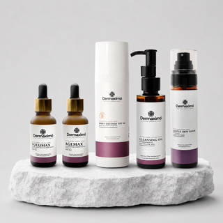 A set of Dermaximó skincare products arranged on a white stone slab against a light gray background. The products include two amber dropper bottles, one amber pump bottle, and one tall white tube, all with white labels and purple accents.